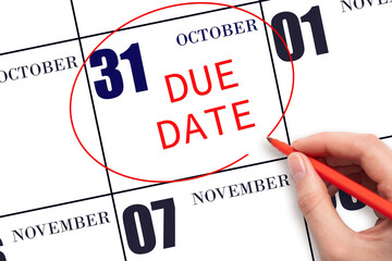 31st day of October. Hand writing text DUE DATE on calendar date October 31 and circling it. Payment due date. Business concept. Autumn month, day of the year concept.