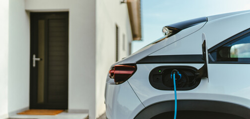 Charging an electric car in home,sustainable transportation concept. - obrazy, fototapety, plakaty