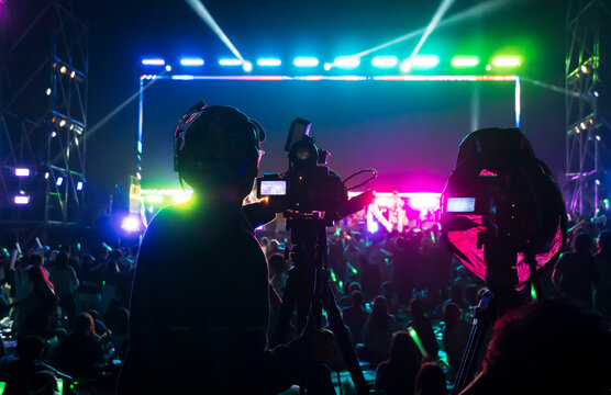 Silhouette of the cameraman records and broadcasts live concerts on professional video recording business camcorders.
