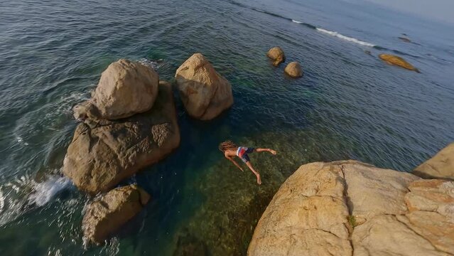 fpv drone flight man jumps off a cliff into the sea