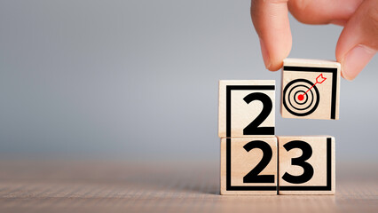 Target plan icon in wooden cubes stacking by hand and 2023 business Achievement and success and growing concept. 2023 goal strategies challenge, Sustainable development.