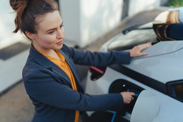 Young woman charging her electric car in home, sustainable and economic transportation concept.