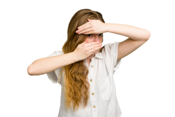 Young caucasian redhead woman isolated blink at the camera through fingers, embarrassed covering face.