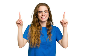 Young caucasian redhead woman isolated indicates with both fore fingers up showing a blank space.