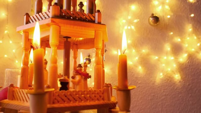 Christmas pyramid rotates with nativity scene and wood carving Christmas characters, traditional german christmas decoration, burning candle in dark room, christmas symbol, waiting for miracle