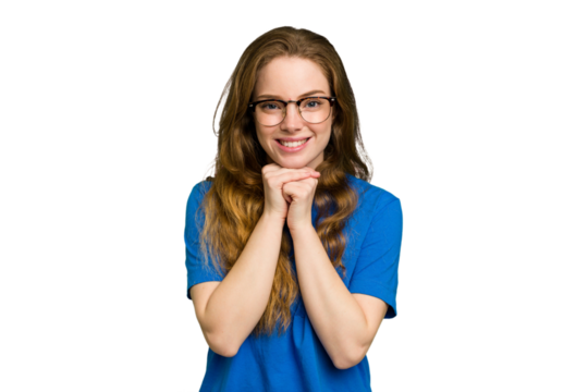 Young caucasian redhead woman isolated keeps hands under chin, is looking happily aside.