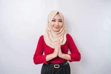 Fototapeta premium Portrait of a young beautiful Muslim woman wearing a hijab gesturing Eid Mubarak greeting