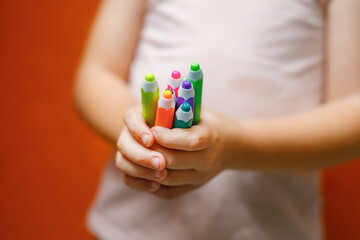 Closeup of hands little preschooler girl holding colorful pencils . Playful child with pencils. Imagination and creativity at school concept.
