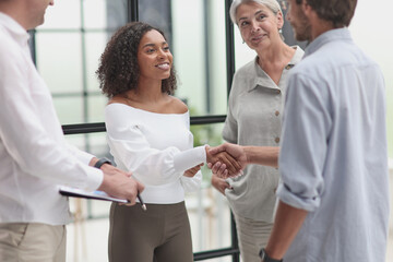 Obraz premium Smiling multiethnic businesspeople shaking hand in office