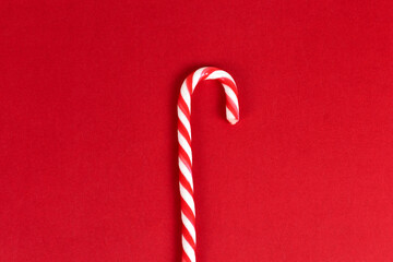 Red minimalistic christmas background with a candy cane top view with copy space.