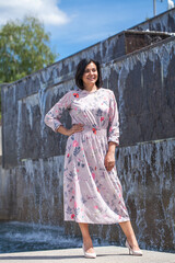 Portrait of a young beautiful woman posing against the backdrop of a city fountain