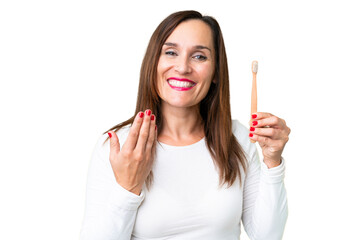 Middle age woman brushing teeth over isolated chroma key background inviting to come with hand. Happy that you came