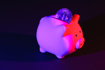 Piggy bank on a dark background with Bitcoin and purple pink backlight. Banking concept. Bitcoin mining concept