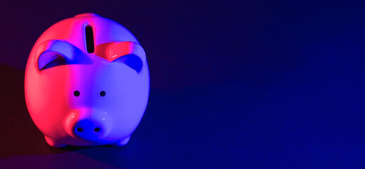 Piggy bank on a dark background with red-blue backlight. Banking concept. Bright neon lights on a black background. Banner
