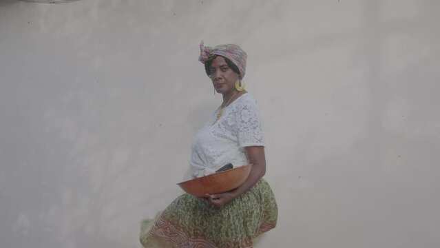 Elder Caribbean woman standing with bowl