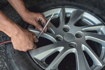 A man uses a stick type gauge to measure the air pressure of recently vulcanized tire.