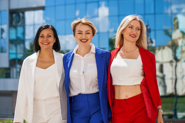 three happy business women posing against the backdrop of the office center