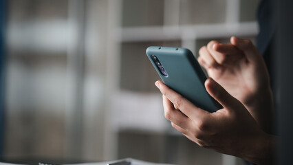 Beautiful Asian woman playing mobile phone in her break from work, she is a marketing manager of a...