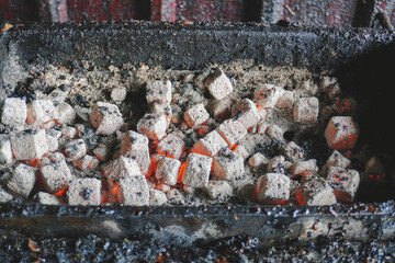 A portrait of close-up barbeque grill pit with flaming hot coal briquettes