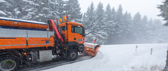 snow plow truck clearing the mountain road in a snow storm