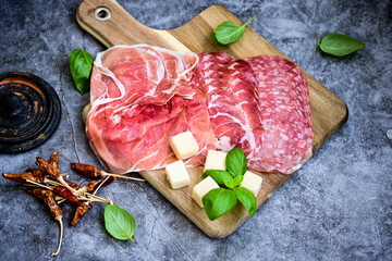 Slices Of  Traditional Italian antipasti mortadella Bolognese,salame Milano, parmesan cheese  and prosciutto crudo   on a wooden  cutting board.