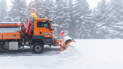 side view of snow plow truck clearing the mountain road in a snow storm