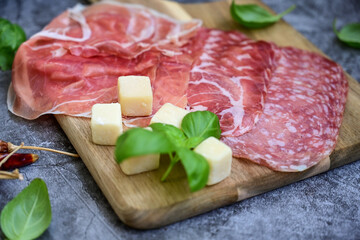 Slices Of  Traditional Italian antipasti mortadella Bolognese,salame Milano, parmesan cheese  and prosciutto crudo   on a wooden  cutting board.
