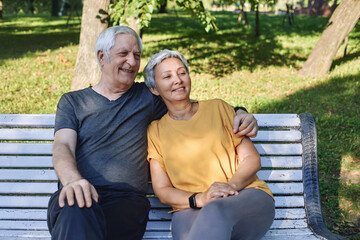 Elderly couple talking resting sit on bench in park