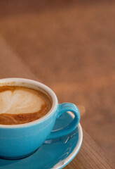 Gran taza de café con leche caliente en una cafetería mientras teletrabajas con el portátil con el fondo desenfocado del suelo.