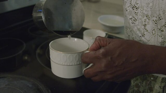 Pouring tea into cup on the stove