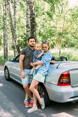 Fototapeta na wymiar Mom, dad and little son in a convertible car. Summer family road trip to nature
