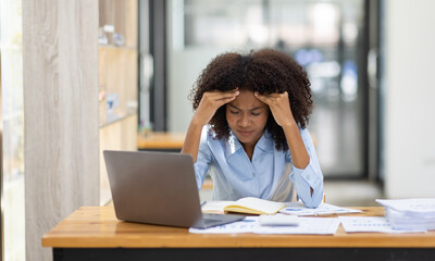 Portrait of tired young business african american woman work with documents tax laptop computer in...