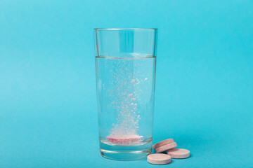 Effervescent tablet in a glass of water on a blue background. Vitamins. Health concept. Immunity drug. Space for copy. Space for text.