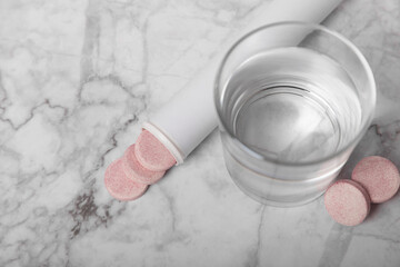Effervescent tablet and a glass of water on a white marble background. Vitamins. Health concept. Immunity drug. Space for copy. Space for text.