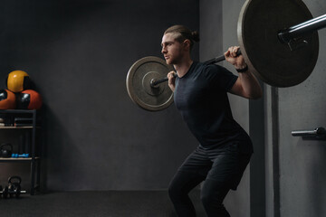 Crossfit athlete lifting barbell in dark workout gym. Functional and circuit training concept. Copy space