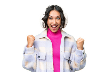 Young Argentinian woman wearing winter muffs over isolated background celebrating a victory in...