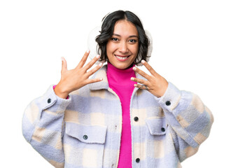 Young Argentinian woman wearing winter muffs over isolated background counting nine with fingers