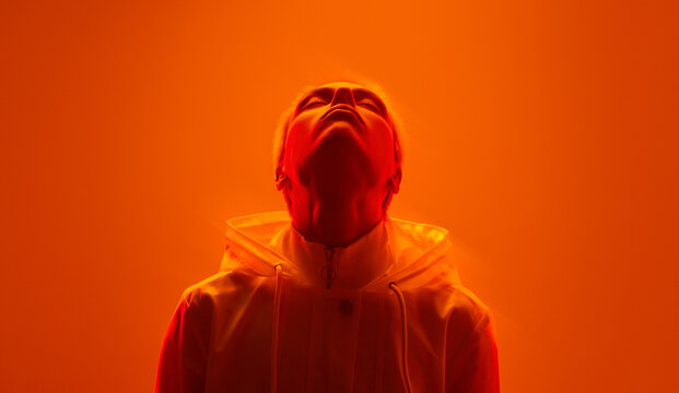 Young informal woman with closed eyes in neon orange studio