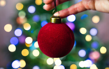 A woman's hands hold a Christmas red ball for Christmas tree decoration. Festive mood. Close-up. Selective focus.