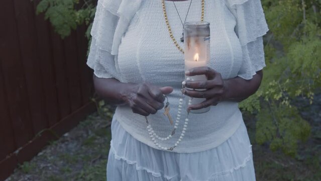 Woman praying rosary with candle lit