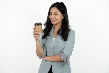 Portrait of a smiling asian businesswoman carrying cup of coffee to go while standing isolated over white background.