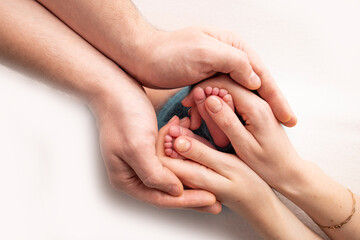 Children's foot in the hands of mother, father, parents. Feet of a tiny newborn close up. Little baby legs. Mom and her child. Happy family concept. Beautiful concept image of motherhood stock photo. 