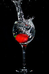 Splash photography capturing an strawberry inside a glass cup 