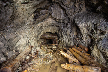 Old gold mine underground tunnel with collapsed wooden timbering