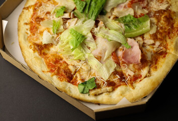 juicy tasty fragrant pizza with greens sausage and cheese in a cardboard box close-up. for labels, splash screens, signage