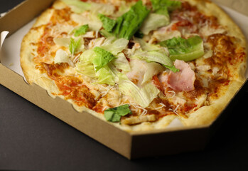 juicy tasty fragrant pizza with greens sausage and cheese in a cardboard box close-up. for labels, splash screens, signage