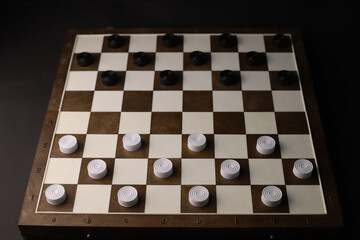 logical and educational checkers game for family and friends. white and black checkers on a brown...