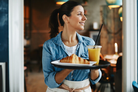 Smiling waitress carrying an order of food to cafe customers