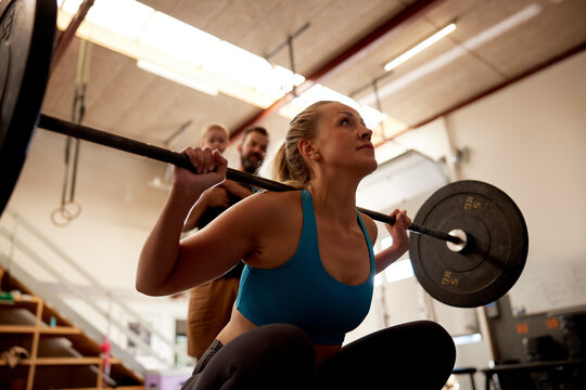 Woman lifting weights with her family watching