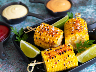 grilled yellow head corn with spices lime close up white red orange sauce portion